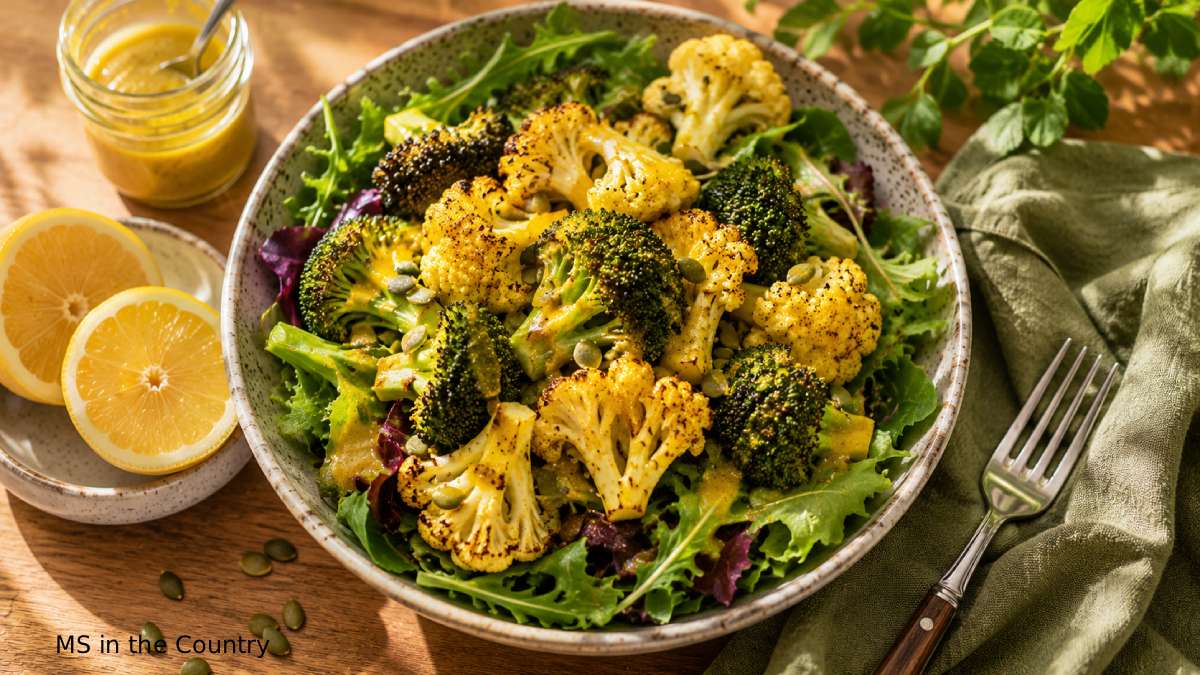 Roasted cauliflower and broccoli bowl over mixed greens with turmeric lemon dressing, showing what to eat with MS for an anti-inflammatory meal