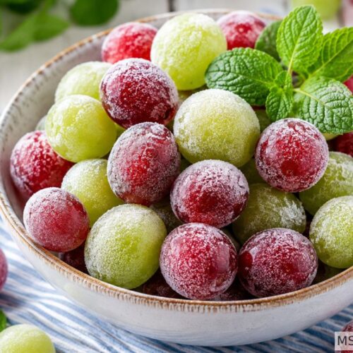 Frozen grapes healthy summer snack with red and green grapes in a white bowl garnished with fresh mint
